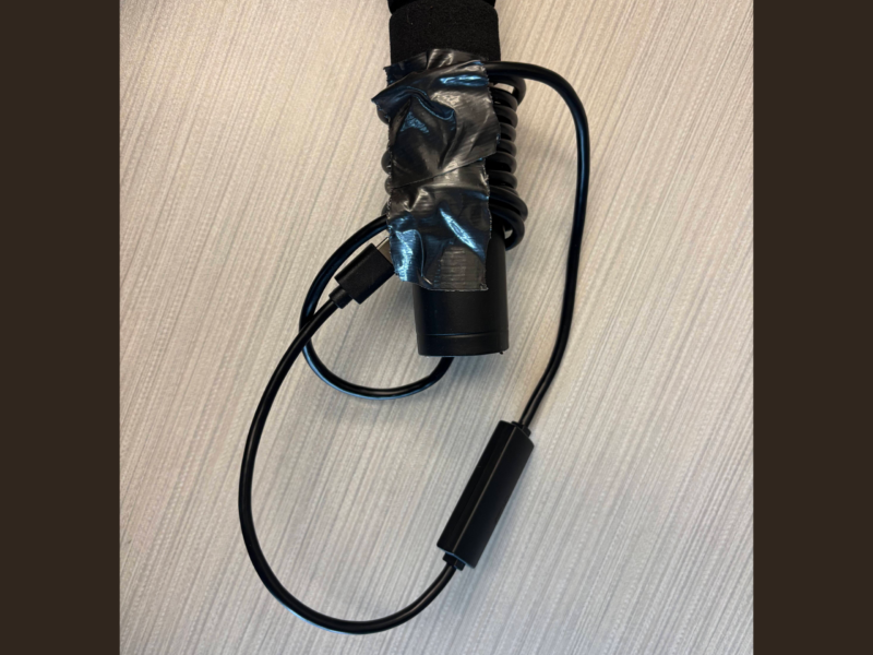 Step Four The handle end of a long hollow pole, with duct tape holding the end of an endoscope in place. Some of the excess endoscope wire has been coiled around the pole handle.